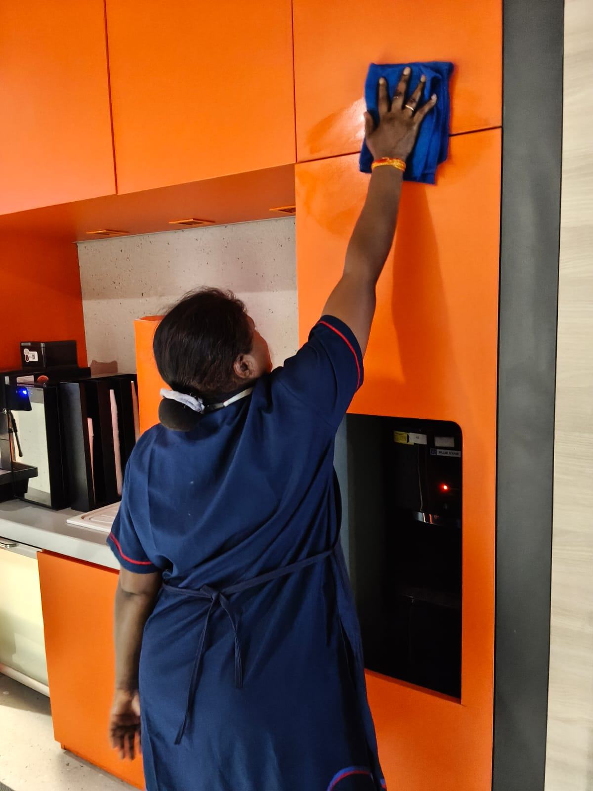 A Manasvi team member carefully cleaning a workplace
